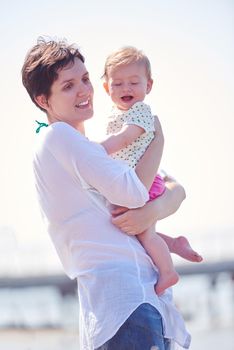 happy mom and baby on beach  have fun while learning to walk and  make first steps