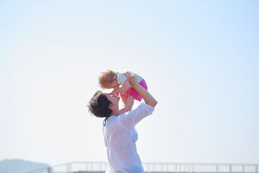 happy mom and baby on beach  have fun while learning to walk and  make first steps