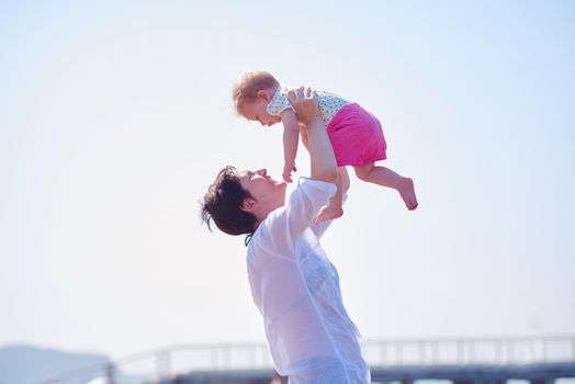 happy mom and baby on beach  have fun while learning to walk and  make first steps