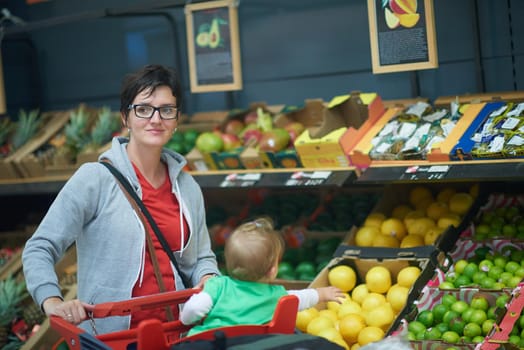 young mother with baby in shopping mall supermarket store buying food and grocery