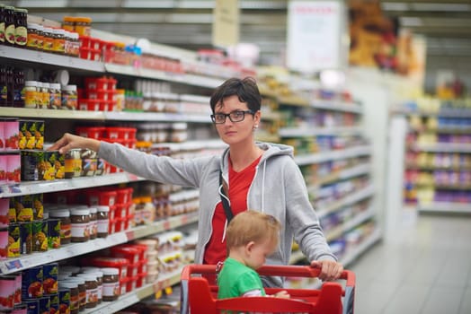 young mother with baby in shopping mall supermarket store buying food and grocery