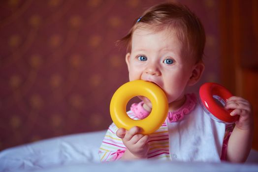 happy baby with first teeth smilling and play with toys