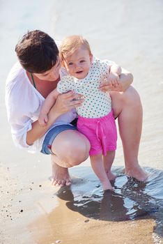 happy mom and baby on beach  have fun while learning to walk and  make first steps