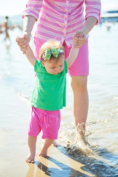 happy mom and baby on beach  have fun while learning to walk and  make first steps