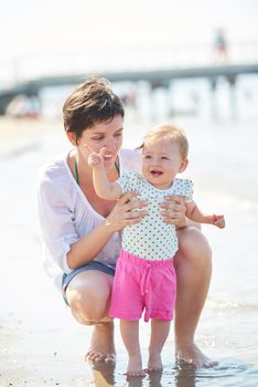 happy mom and baby on beach  have fun while learning to walk and  make first steps