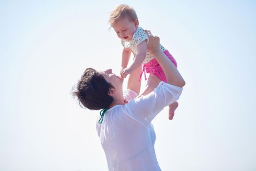 happy mom and baby on beach  have fun while learning to walk and  make first steps