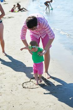 happy mom and baby on beach  have fun while learning to walk and  make first steps