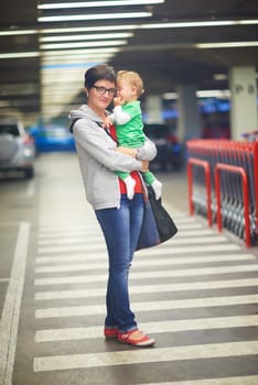 young mother with baby in shopping mall supermarket store buying food and grocery