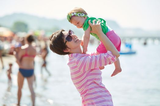 happy mom and baby on beach  have fun while learning to walk and  make first steps