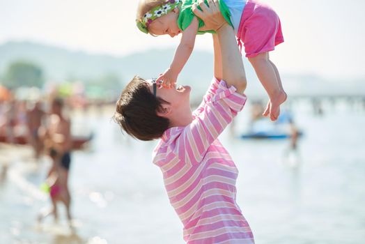 happy mom and baby on beach  have fun while learning to walk and  make first steps