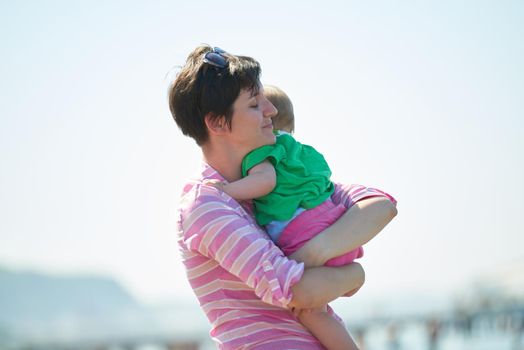 happy mom and baby on beach  have fun while learning to walk and  make first steps