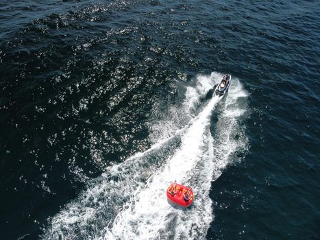 Inflatable attraction. Happy people are going to swim on an air mattress behind a jet ski. Tourists ride the inflatable watercraft boat. Jet ski skating people on a large Inflatable raft