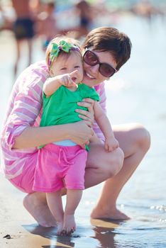 happy mom and baby on beach  have fun while learning to walk and  make first steps