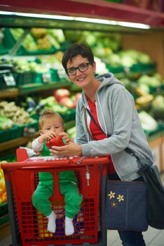 young mother with baby in shopping mall supermarket store buying food and grocery