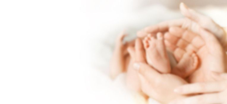 blurred image for the advertising text. legs newborn baby in the hands of his parents . the concept of parenthood