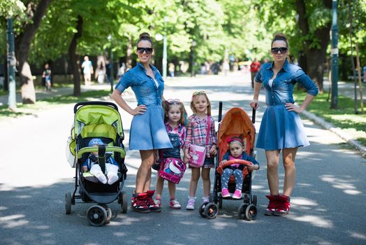 Young beautiful twins mother with children enjoying a sunny day in city park