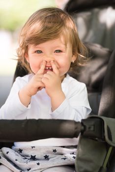 little and very beautiful baby girl sitting in the pram and waiting for mom