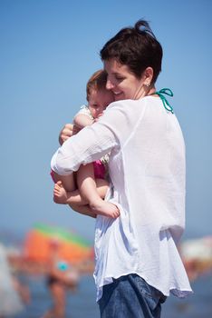 happy mom and baby on beach  have fun while learning to walk and  make first steps