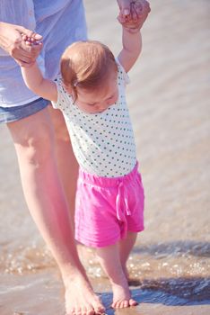 happy mom and baby on beach  have fun while learning to walk and  make first steps