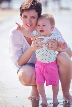 happy mom and baby on beach  have fun while learning to walk and  make first steps