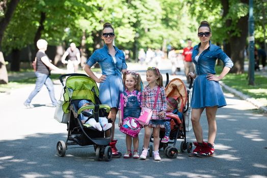 Young beautiful twins mother with children enjoying a sunny day in city park