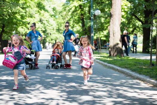 Young beautiful twins mother with children enjoying a sunny day in city park