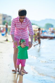 happy mom and baby on beach  have fun while learning to walk and  make first steps