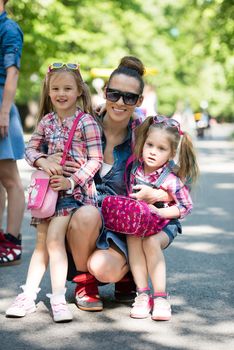 young beautiful mother enjoying with her daughters on a sunny day in the park