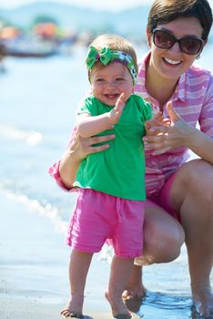 happy mom and baby on beach  have fun while learning to walk and  make first steps