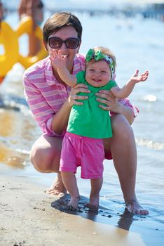 happy mom and baby on beach  have fun while learning to walk and  make first steps