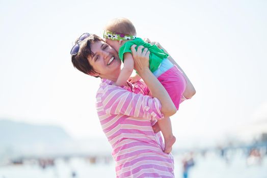 happy mom and baby on beach  have fun while learning to walk and  make first steps