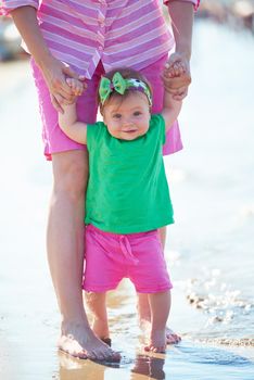 happy mom and baby on beach  have fun while learning to walk and  make first steps