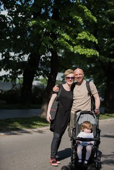 love, parenthood, family, season and people concept  Portrait of a young smiling couple with baby pram in summer park