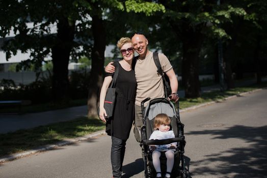 love, parenthood, family, season and people concept  Portrait of a young smiling couple with baby pram in summer park