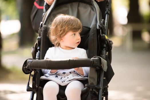 little and very beautiful baby girl sitting in the pram and waiting for mom