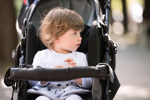 little and very beautiful baby girl sitting in the pram and waiting for mom