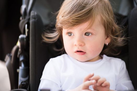 little and very beautiful baby girl sitting in the pram and waiting for mom