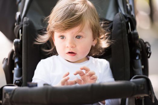 little and very beautiful baby girl sitting in the pram and waiting for mom