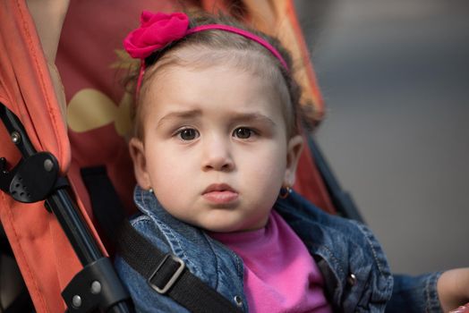 little and very beautiful baby girl sitting in the pram and waiting for mom