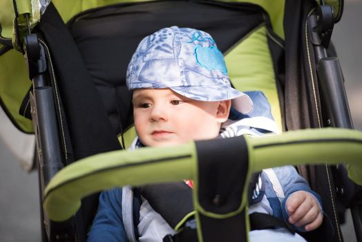 little and very beautiful baby boy sitting in the pram and waiting for mom