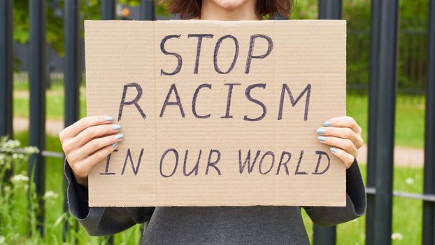 Stop racism concept. Unrecognizable person holds sign with text against racist. White people protests in demonstration