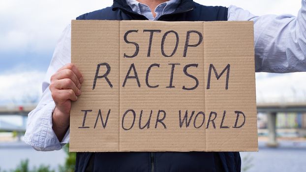 Stop racism concept. Unrecognizable person holds sign with text against racist. White people protests in demonstration