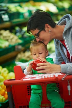 young mother with baby in shopping mall supermarket store buying food and grocery