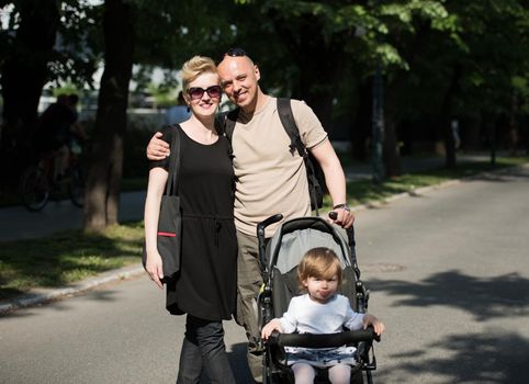 love, parenthood, family, season and people concept  Portrait of a young smiling couple with baby pram in summer park