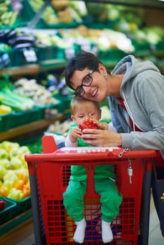 young mother with baby in shopping mall supermarket store buying food and grocery