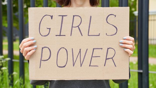 Girl Power concept. Unrecognizable person holds sign with text about feminism. Woman protests in demonstration