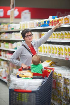 young mother with baby in shopping mall supermarket store buying food and grocery