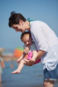 happy mom and baby on beach  have fun while learning to walk and  make first steps