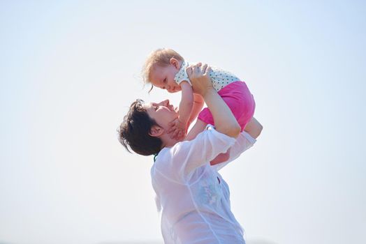 happy mom and baby on beach  have fun while learning to walk and  make first steps