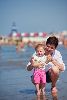 happy mom and baby on beach  have fun while learning to walk and  make first steps